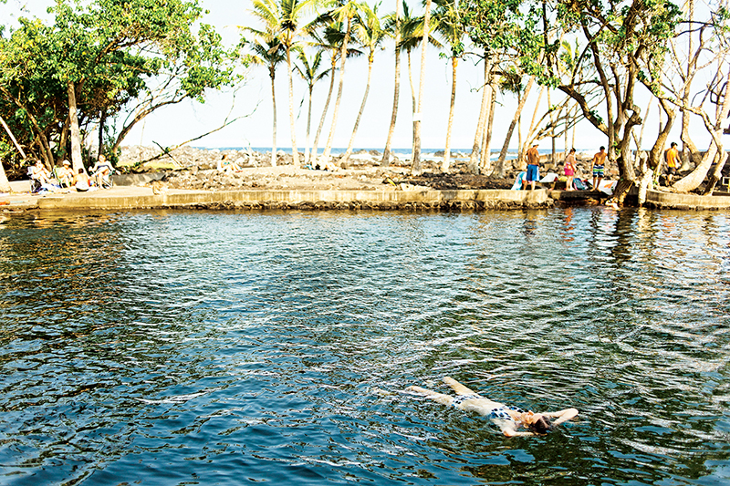 /><figcaption>Ahalanui Beach Park’s warm pool.<br />
<em>Photo: Megan Spelman</em></figcaption></figure>
</div>
<p>I decide to make one last stop at Ahalanui Beach Park for a quick peek at its volcanic hot spring. It’s a large, walled-in natural pool with stairways leading into it, warmed by the water that flowed through hot rocks heated by magma before ending up here. I dip my toes into the lukewarm water then quickly make my way back to the car. It’s getting dark and I don’t want to get lost driving through the pitch-black jungle.</p>
<p>When I arrive at the cabin, the sun is setting and the birds are chirping loudly in the trees. I eat a simple meal under a single lightbulb overhead, get into bed and pull the mosquito netting around me. I stare once more into the night, with just my thoughts and no distractions, reflecting on how this different, and sometimes challenging, experience I’ve created on my own has turned out to be one of the most fulfilling gifts I’ve given to myself.</p>
<hr />
<p><em>This article, </em>“In The Jungle,” <em>was originally published in the May/June 2016 issue of HAWAIʻI Magazine.</em><!-- Simple Share Buttons Adder (8.5.3) simplesharebuttons.com --></p>
<div class=