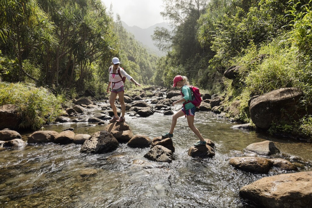 Mother And Daughter Crossing A Creek, Kauai